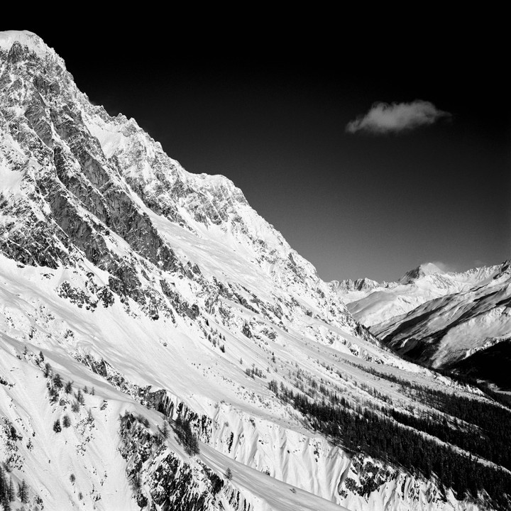 A snow-covered mountain range with a single cloud in the dark sky is visible.