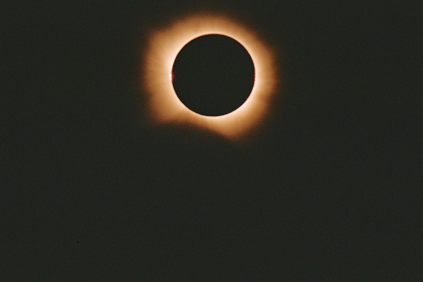 The sun is visible during a total solar eclipse, with a bright corona around the dark disk of the moon.