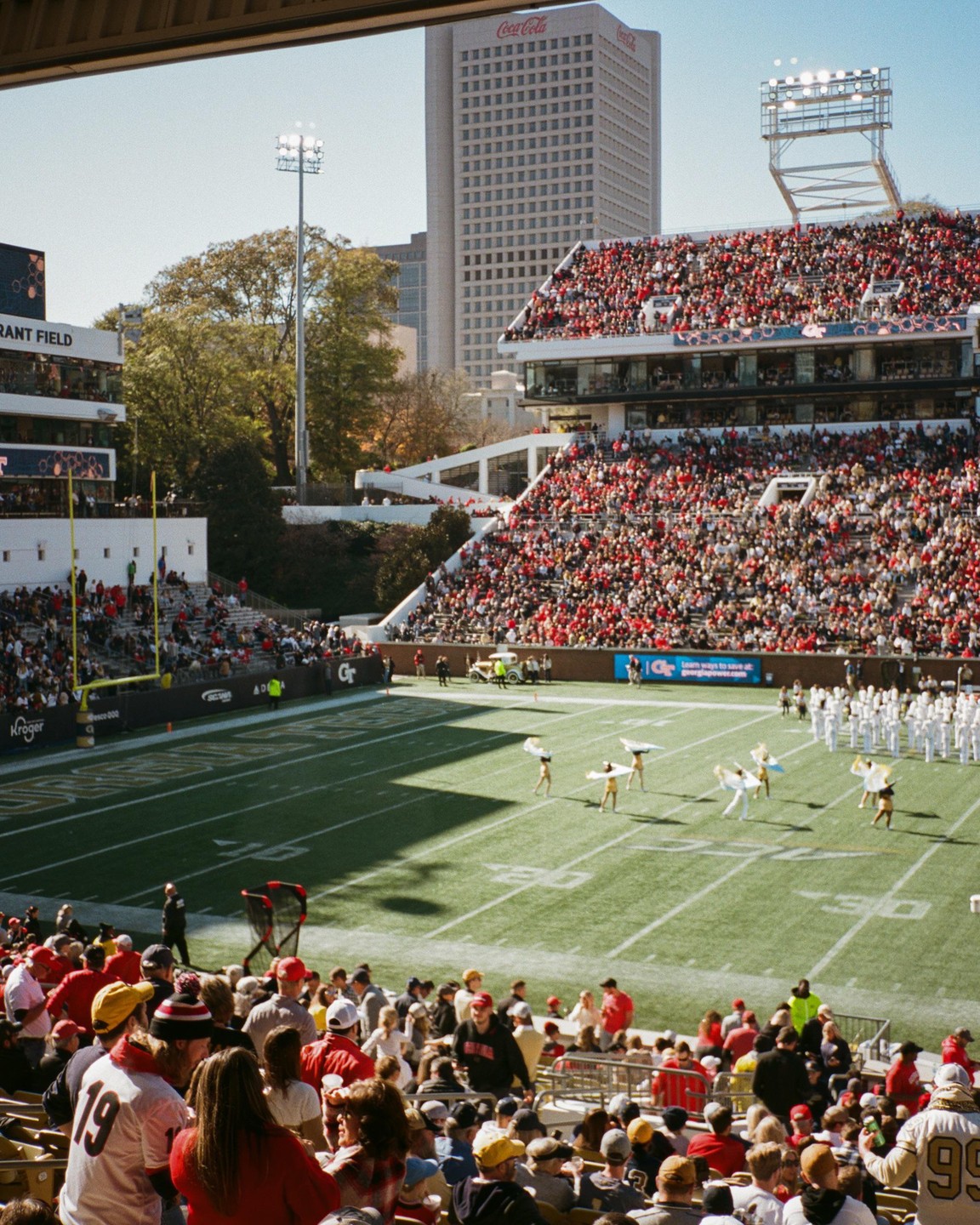 A football stadium is filled with spectators watching a halftime show on the field.