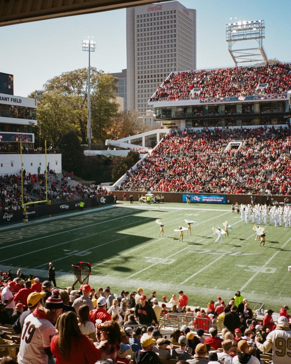 A football stadium is filled with spectators watching a halftime show on the field.