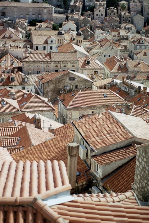An aerial view shows a dense collection of buildings with terracotta roofs in Dubrovnik.