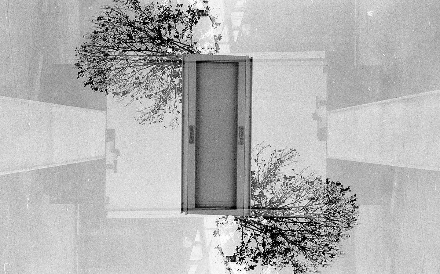 A double exposure shows a door with trees and buildings superimposed on it.