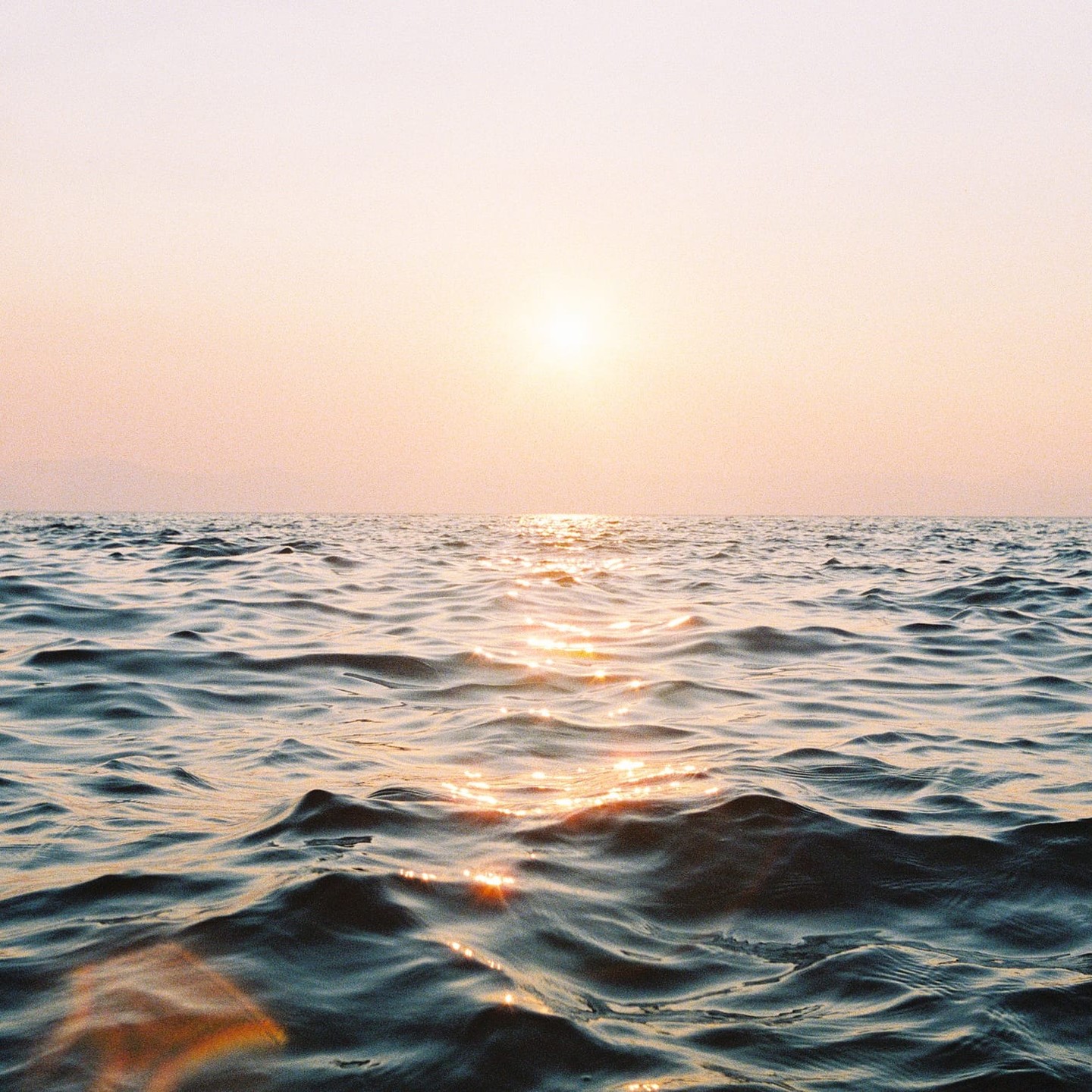 The sun reflects on the surface of the ocean at sunset.