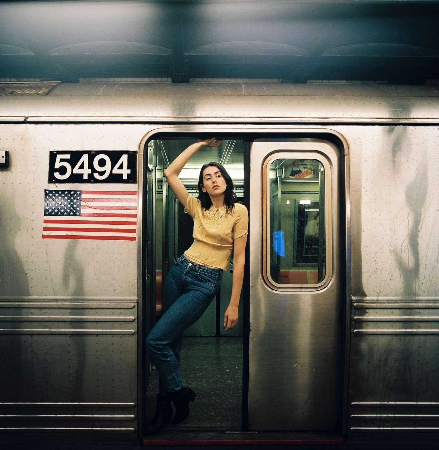 A woman leans out of a subway car door with an American flag sticker on the side.