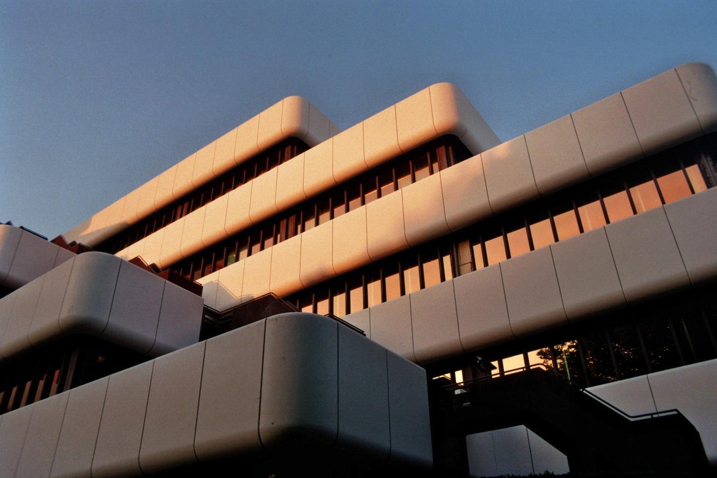A modern building with many windows reflects the golden hour light.