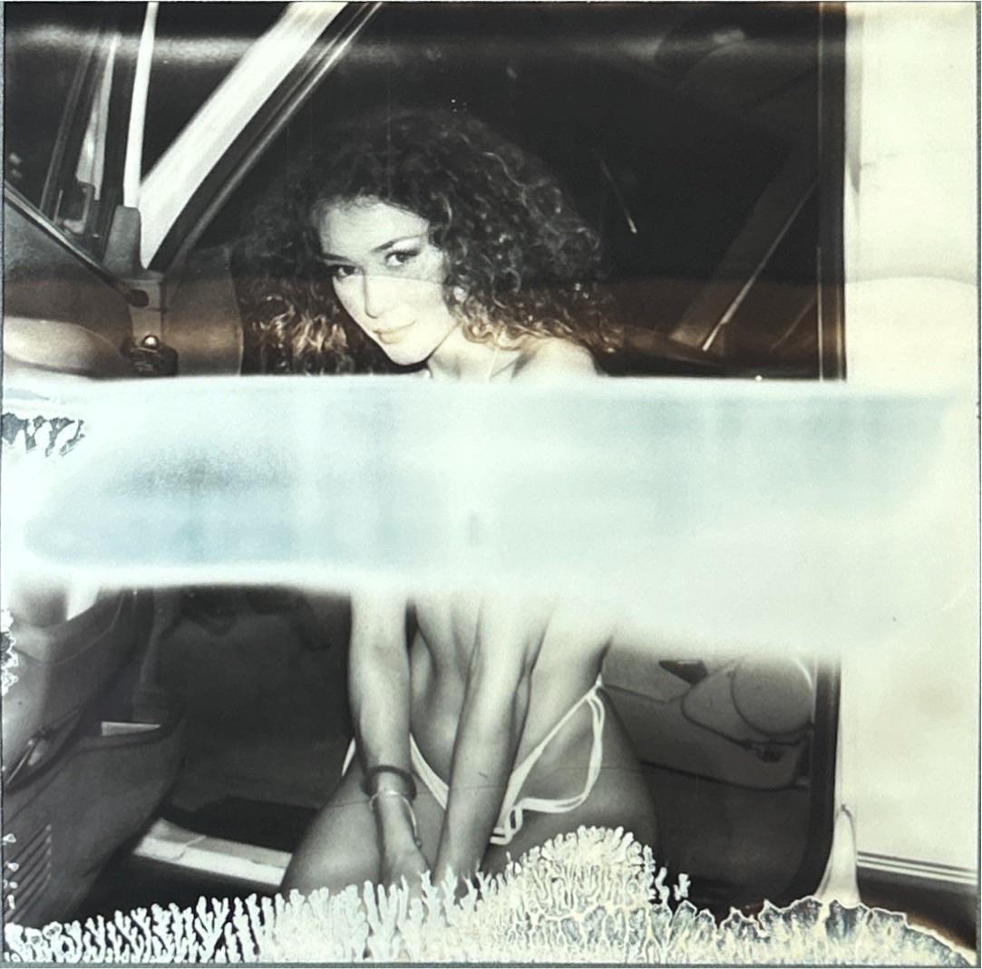 A woman with curly hair is sitting in a car.