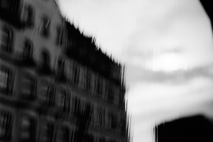 A blurry building is visible through a rain-streaked window.