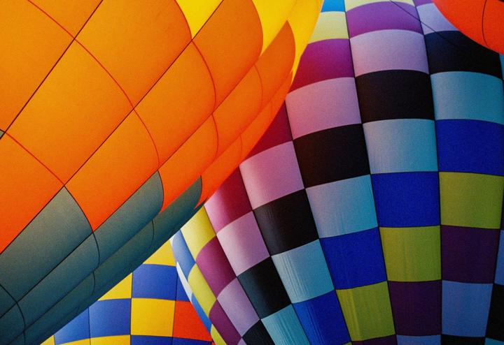 Three hot air balloons with colorful checkered patterns are shown close up.