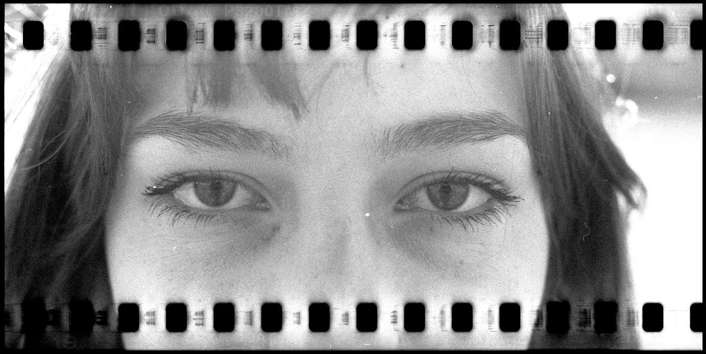 A woman's eyes are visible through a film strip border.