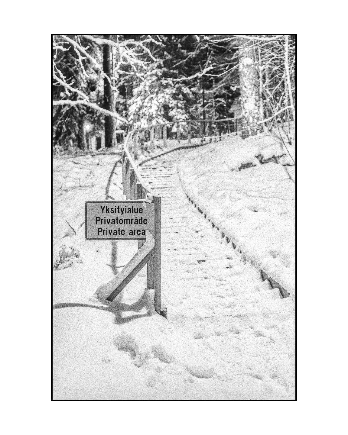 A private area sign stands in a snow-covered landscape with a path and trees.