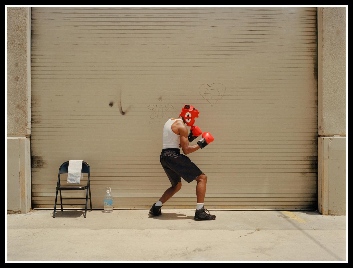 A man in boxing gear is practicing in front of a garage door.