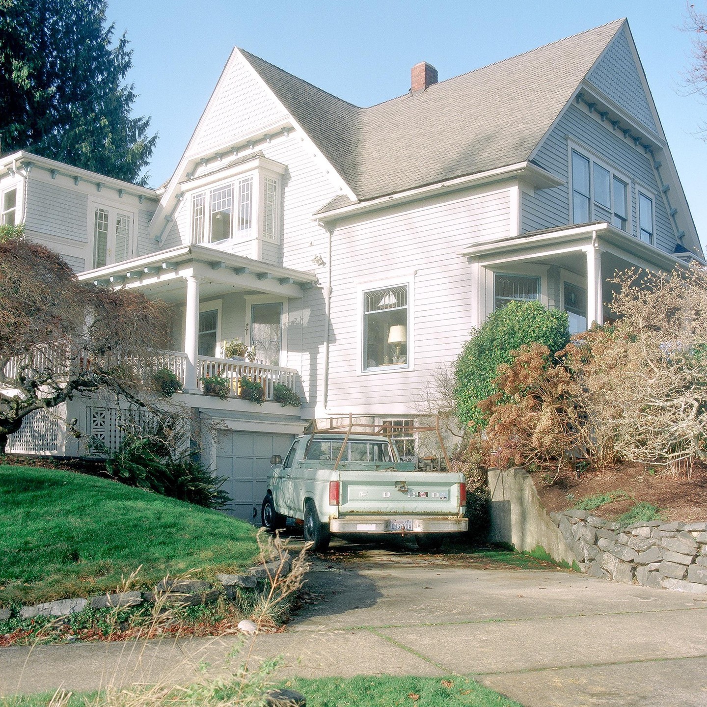 A light blue house with a porch and a light green pickup truck parked in the driveway.