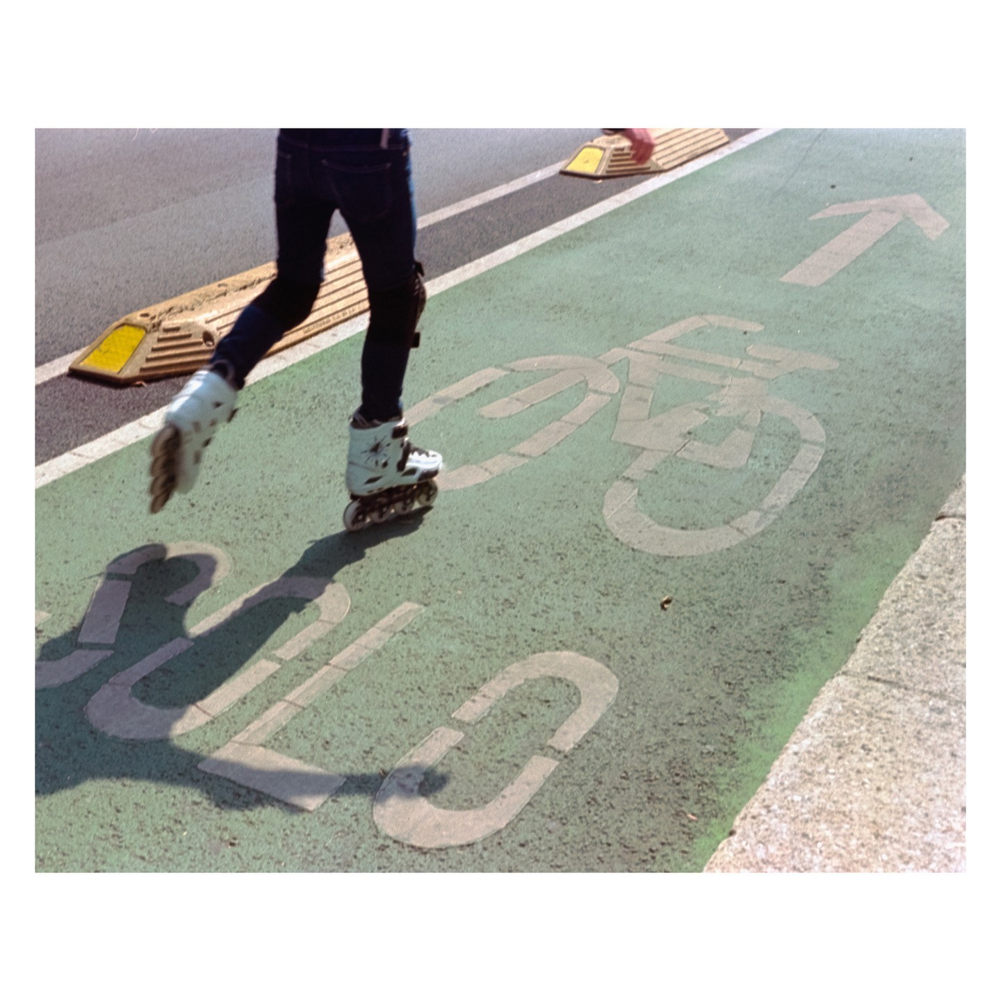 A person on rollerblades moves along a green bike lane with a painted bicycle symbol.