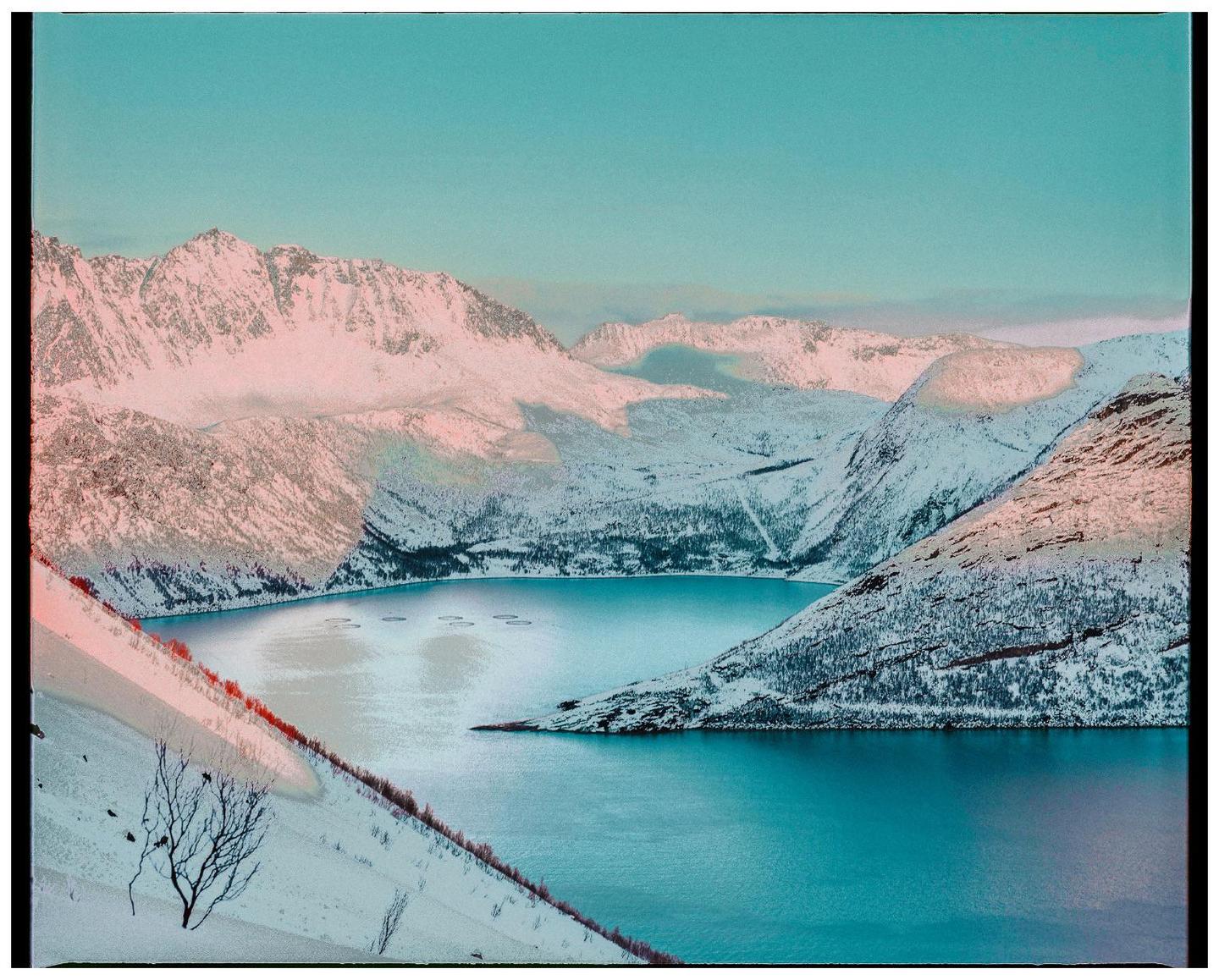 A body of water is surrounded by snow-covered mountains under a clear sky.
