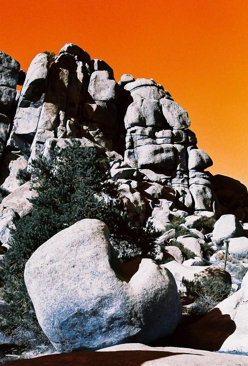 A large rock formation with a bright orange sky in the background.