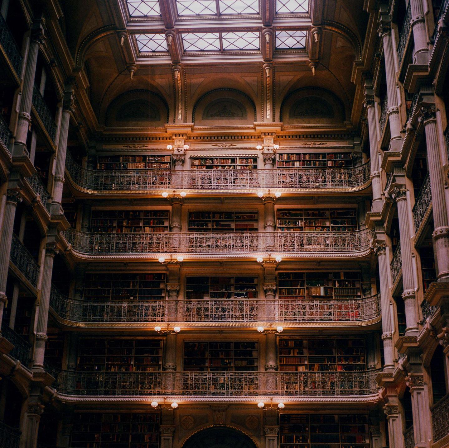 A multi-story library interior with balconies full of books and a skylight is visible.