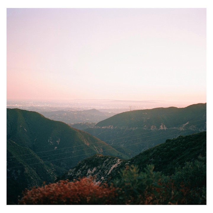 A hazy view of a city in the distance, seen from a mountain with power lines in the foreground.