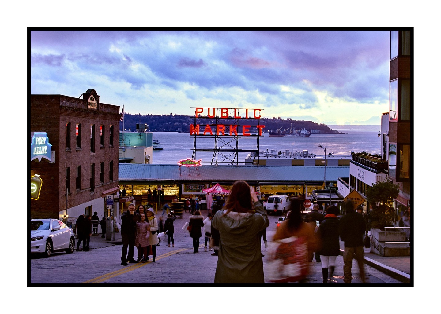 A street scene shows people walking on a cobblestone street with a large "PUBLIC MARKET" sign and water in the background.