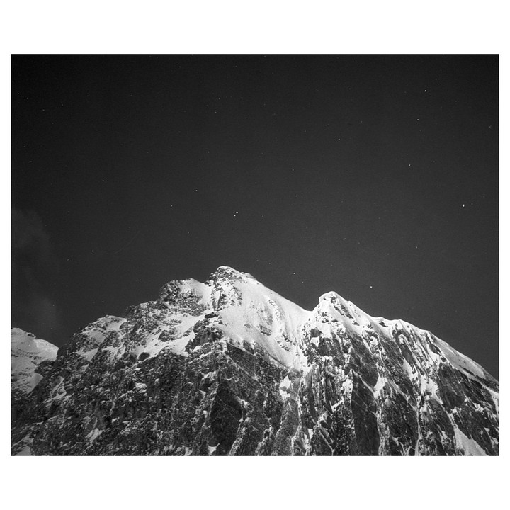 A snow-covered mountain peak is visible under a starry night sky.