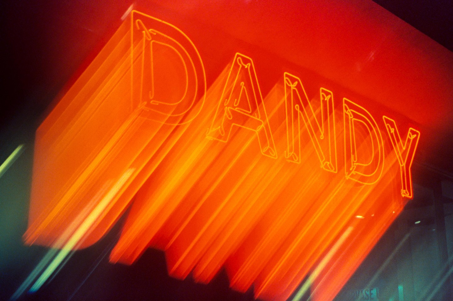The word "DANDY" is written in orange neon lights with a motion blur effect.