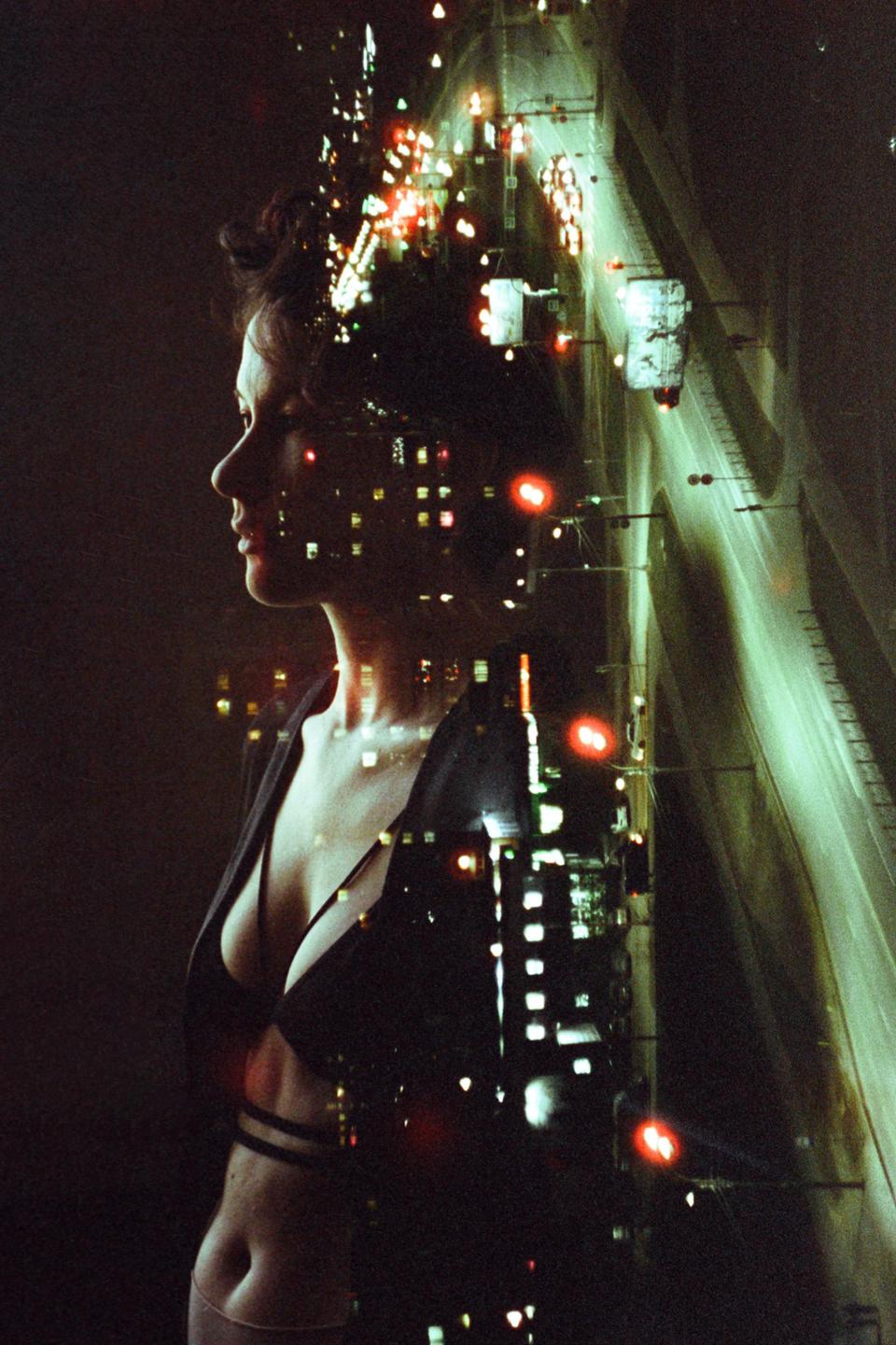 A woman's profile is superimposed over a night cityscape with a highway.