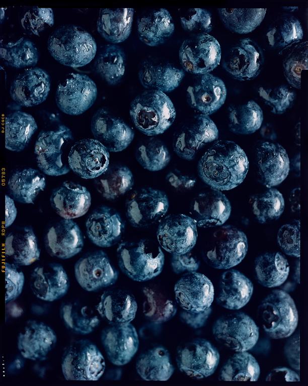 A close-up overhead shot shows many blueberries with water droplets on their surfaces.
