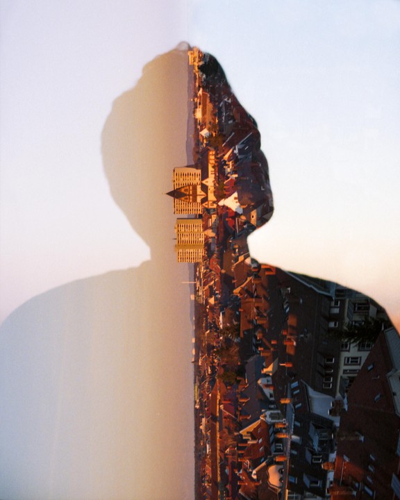 A double exposure shows a silhouette of a person overlaid with a cityscape at sunset.