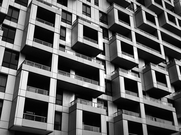 A modern building facade features a complex arrangement of balconies and windows.