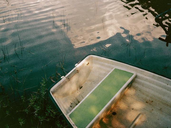 A small boat is partially visible in the water, with reflections of the sky and trees on the surface.