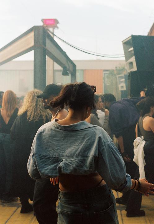 A woman with her back to the camera dances in a crowd of people.