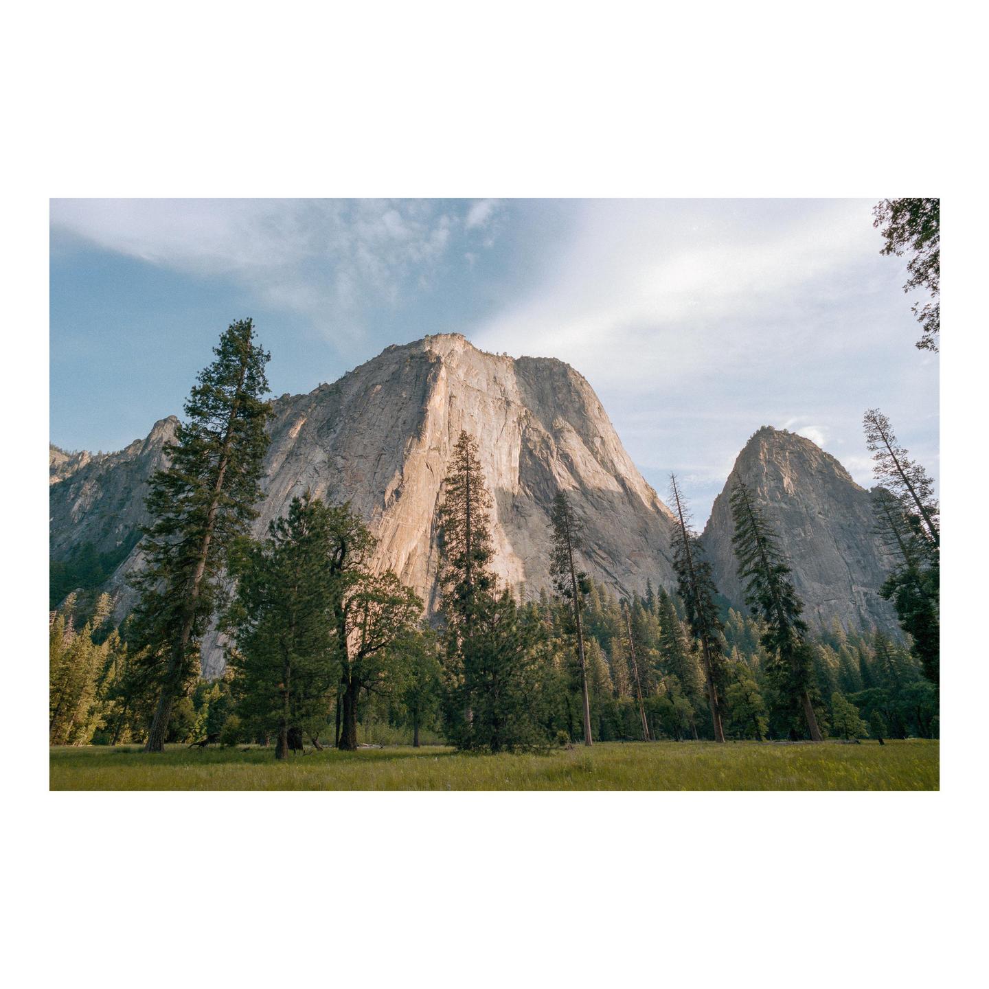 A wide shot shows a valley with a large mountain and many trees.