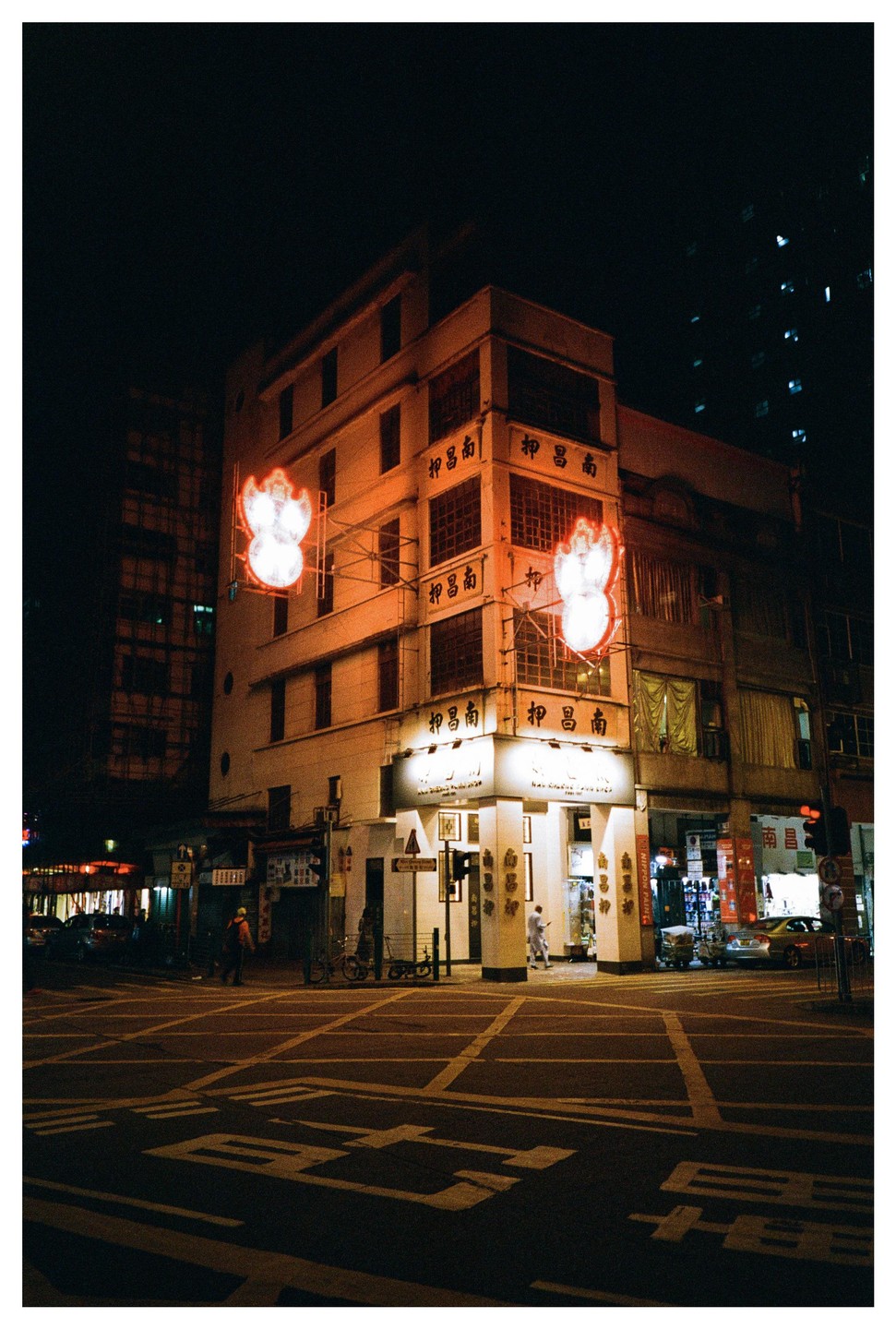 A street corner building with neon signs is illuminated at night.