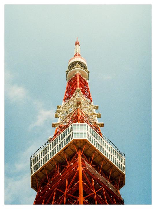 A low-angle view shows the red and white Tokyo Tower against a clear sky.