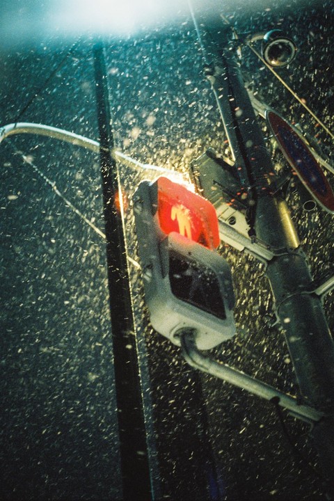 A red pedestrian signal with a "do not walk" symbol is visible on a snowy night.