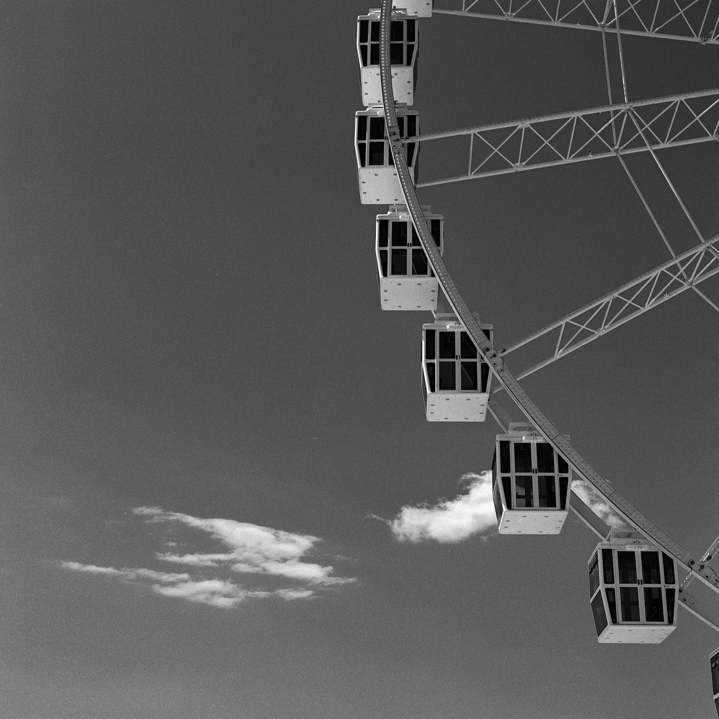 A ferris wheel with multiple gondolas is visible against a clear sky with a few clouds.