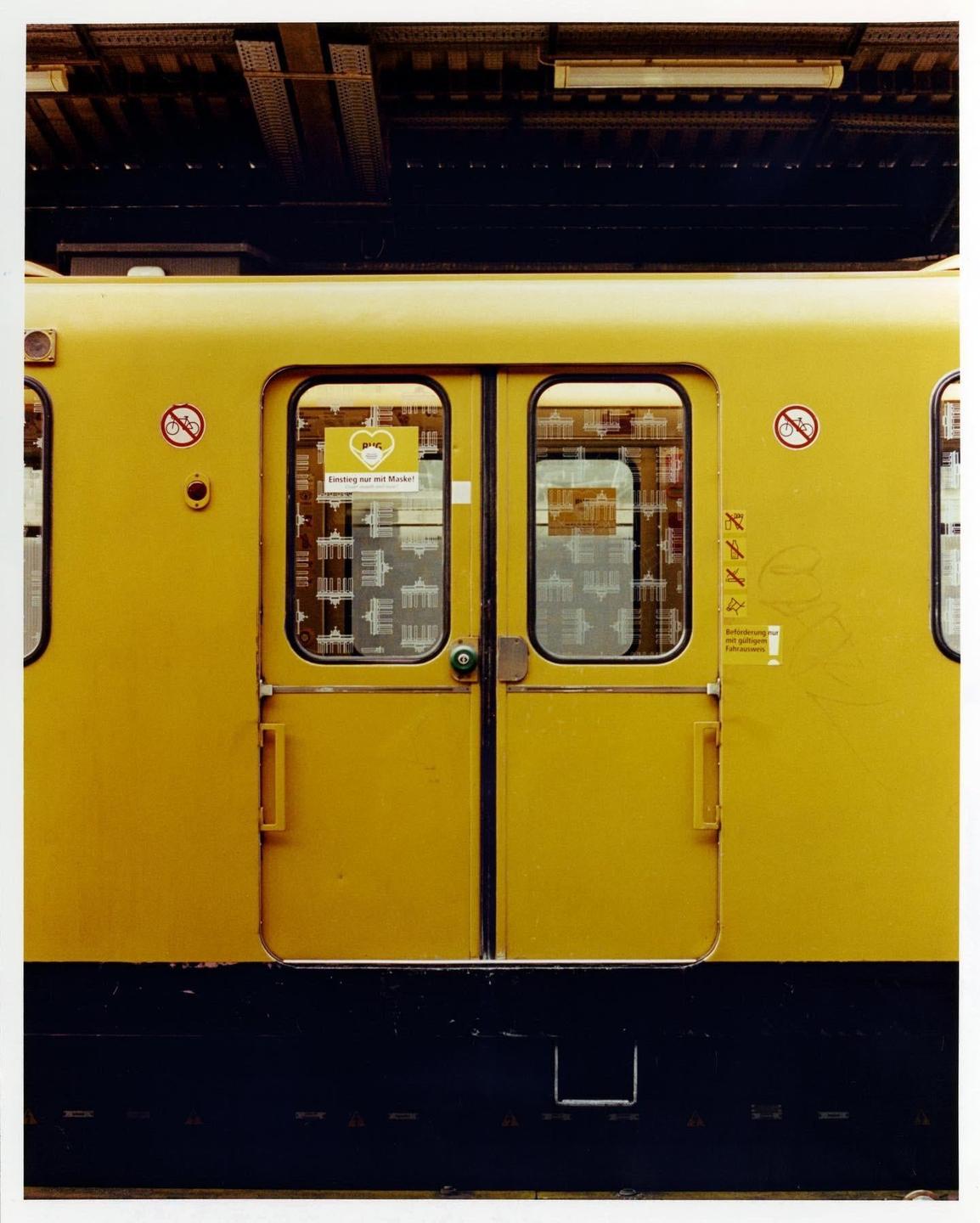A yellow subway car with closed doors is parked at a station platform.