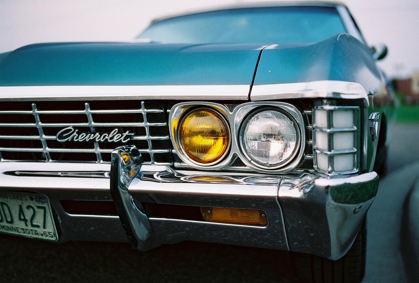 The front of a blue Chevrolet Impala is visible, showing its grille, headlights, and bumper.
