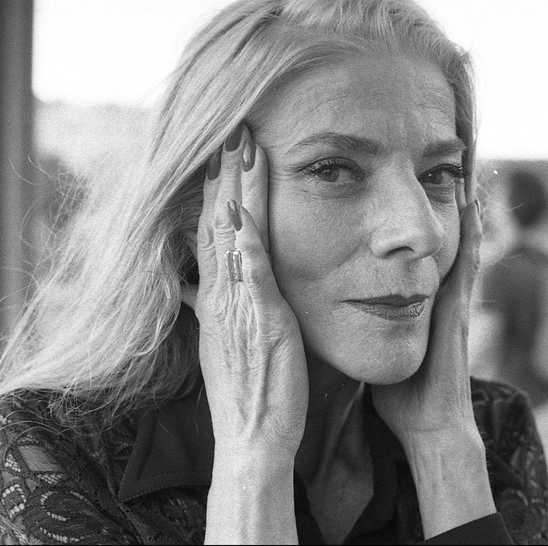 A woman with long hair holds her hands to her face.