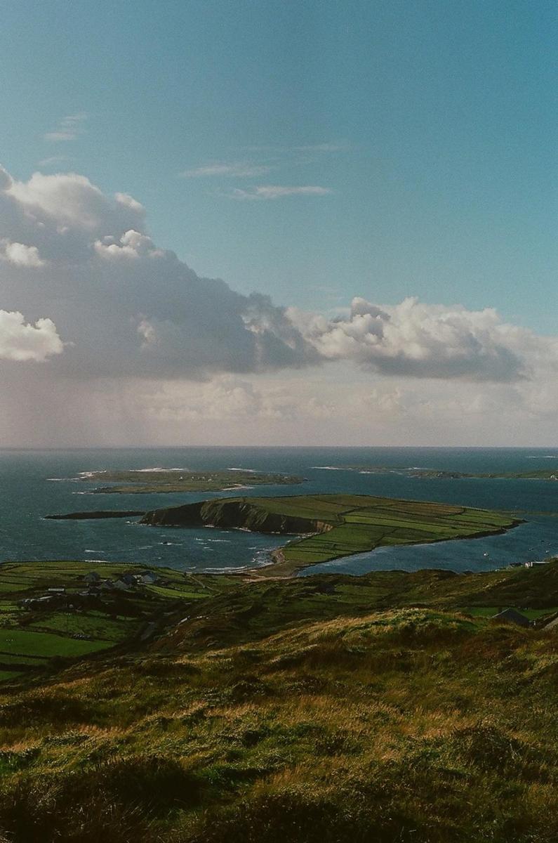 A wide shot shows a body of water with several small islands and green hills in the foreground.