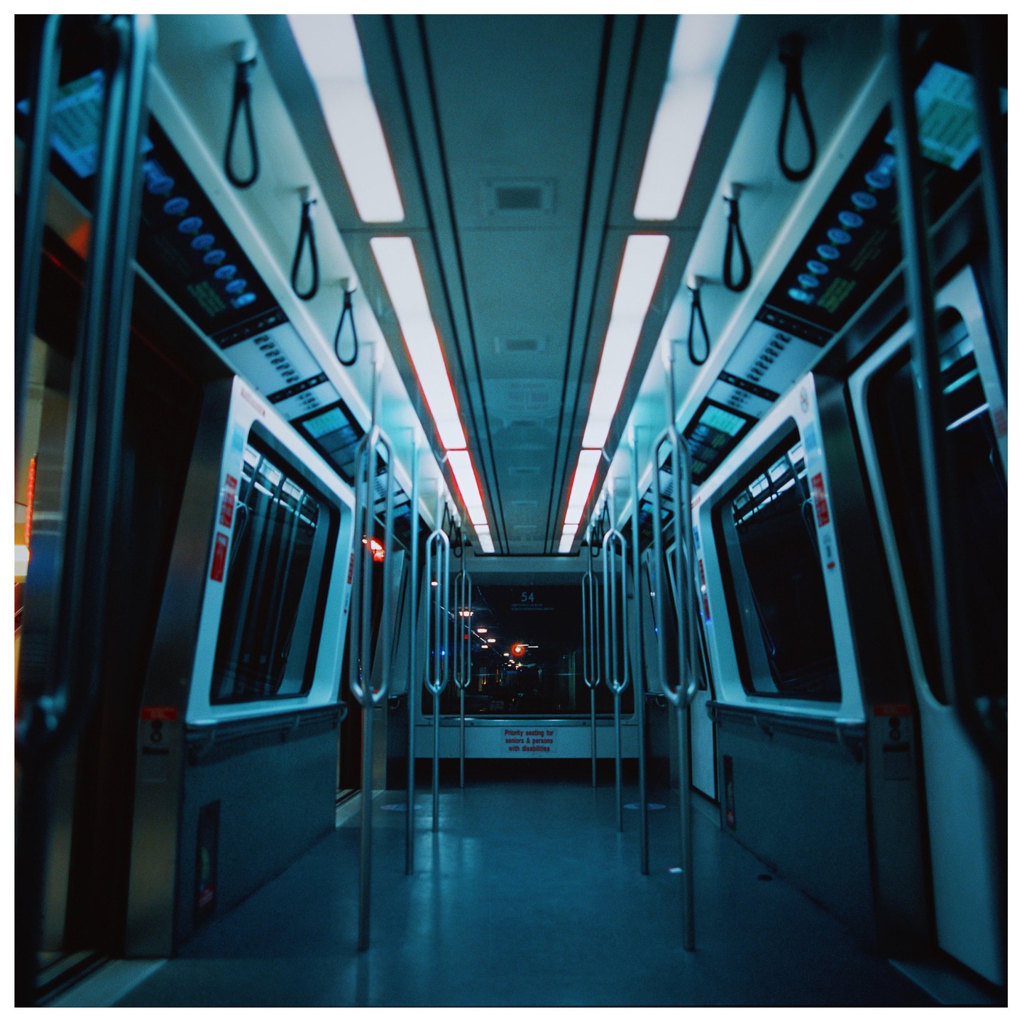 The interior of an empty train car is illuminated by overhead lights.