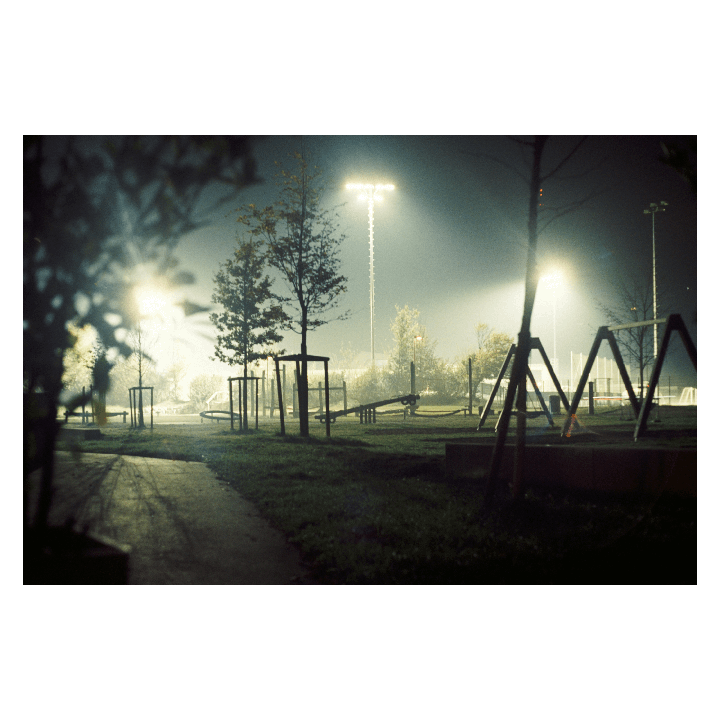 A playground is illuminated by bright lights at night.