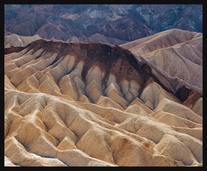 A landscape view shows the colorful, eroded badlands of Death Valley.