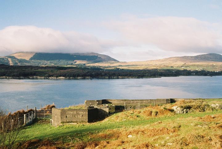A body of water is visible with mountains in the background and a concrete structure in the foreground.