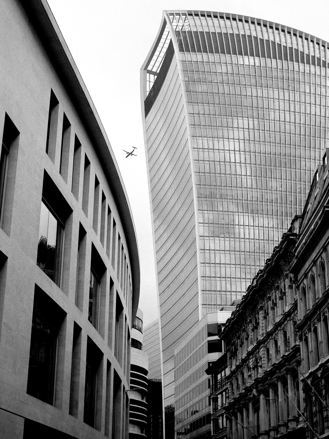 A small airplane flies between two tall buildings in a city.