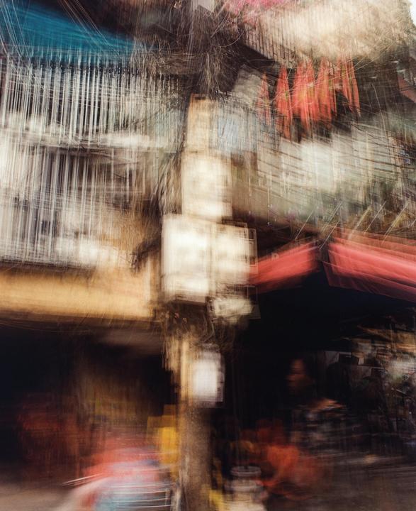 A blurry street scene shows buildings with awnings and a person in the shadows.
