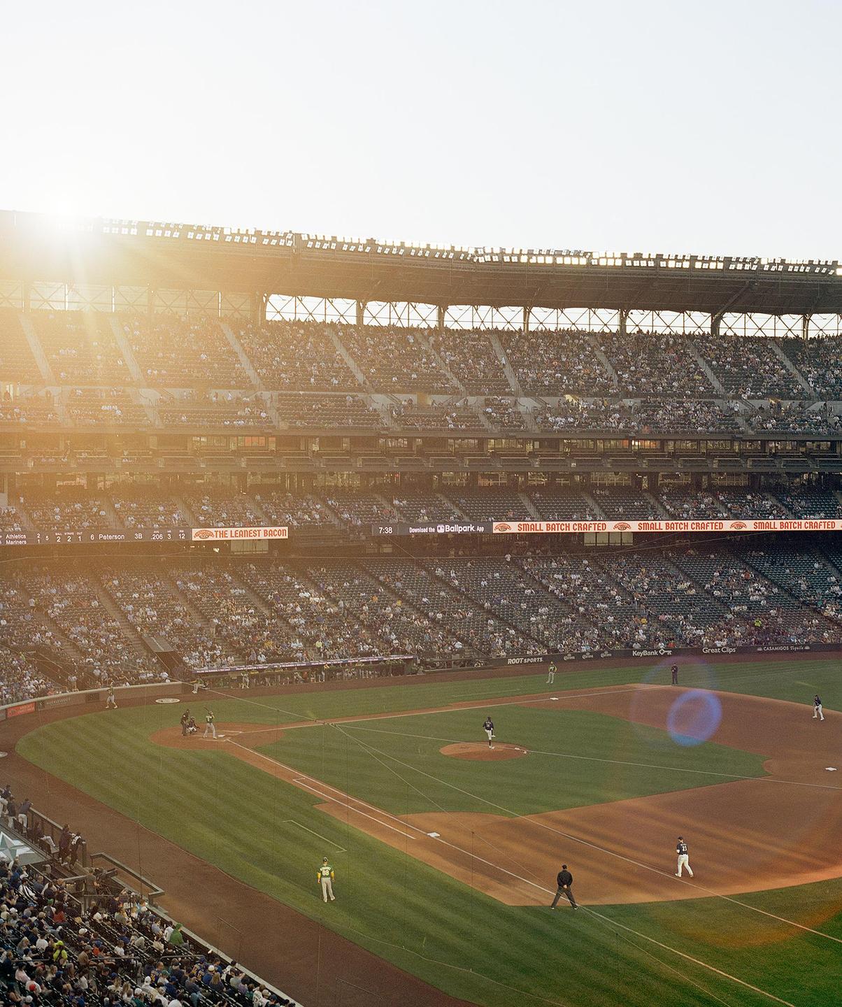 A baseball game is played on a sunny day in a large stadium filled with spectators.