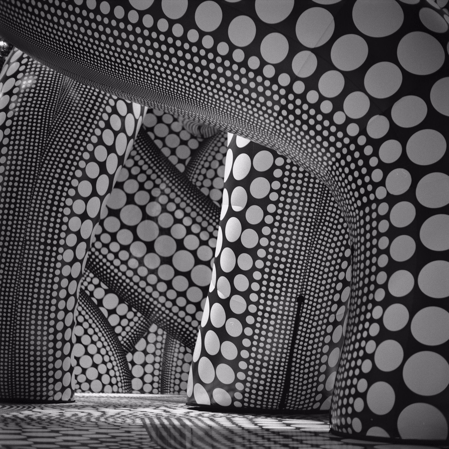 Several large, curved structures covered in black and white polka dots create an immersive, patterned environment.