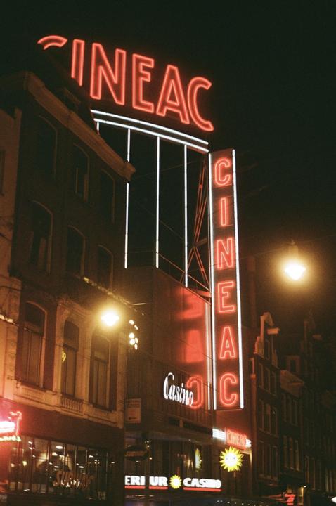 A tall building with a large neon sign for "Cineac" and "Casino" is illuminated at night.