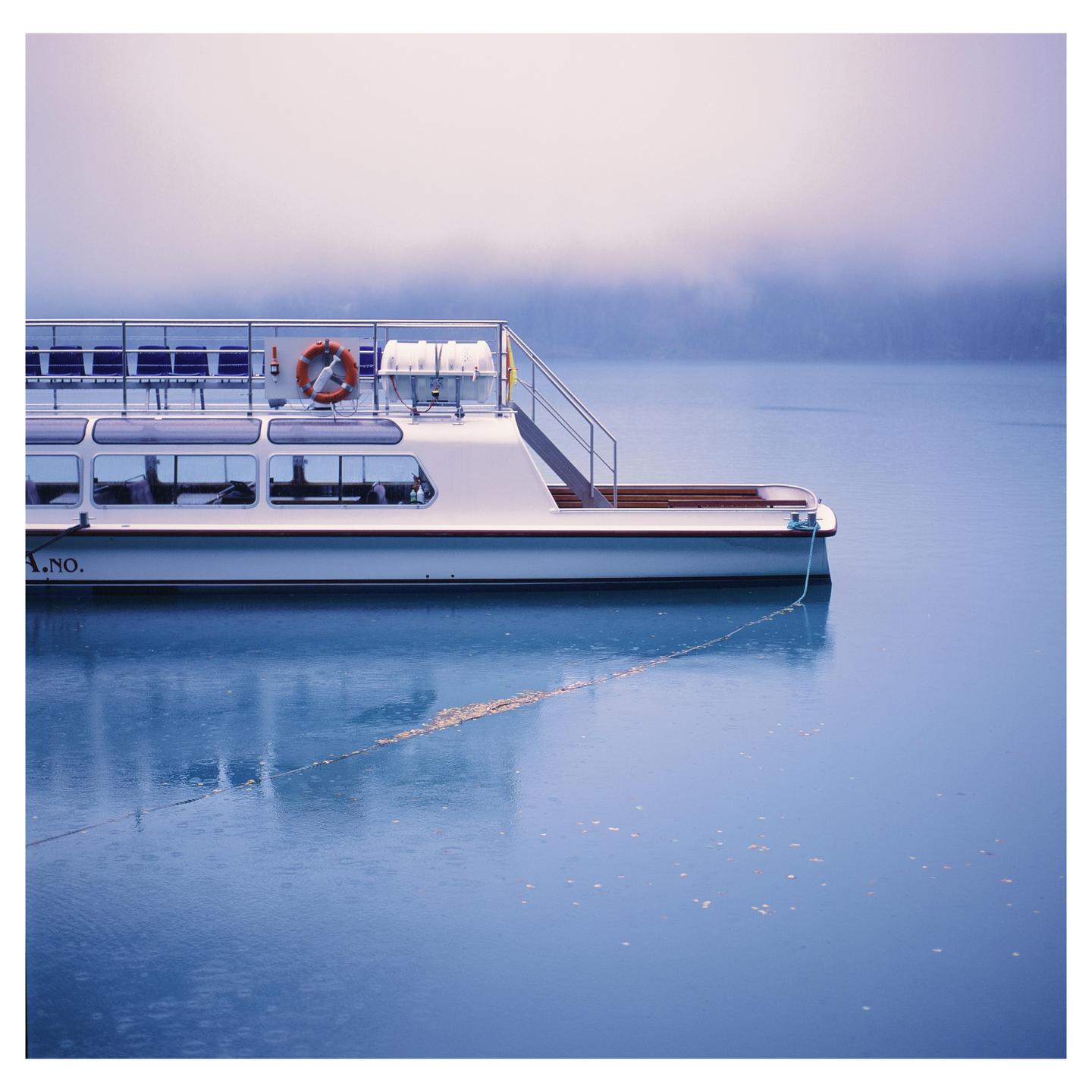 A white boat is docked on a body of water under a hazy sky.