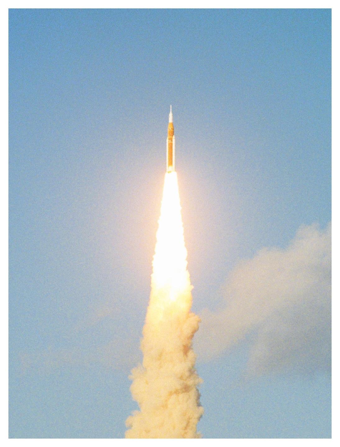A rocket launches into a clear blue sky, leaving a trail of fire and smoke.
